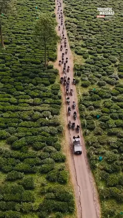 Aerial View of Motorcycle Convoy An aerial view of a massive motorcycle convoy riding through the vast green tea plantations at boCHE 1000 Acre, a top choice for adventure activities in Wayanad.