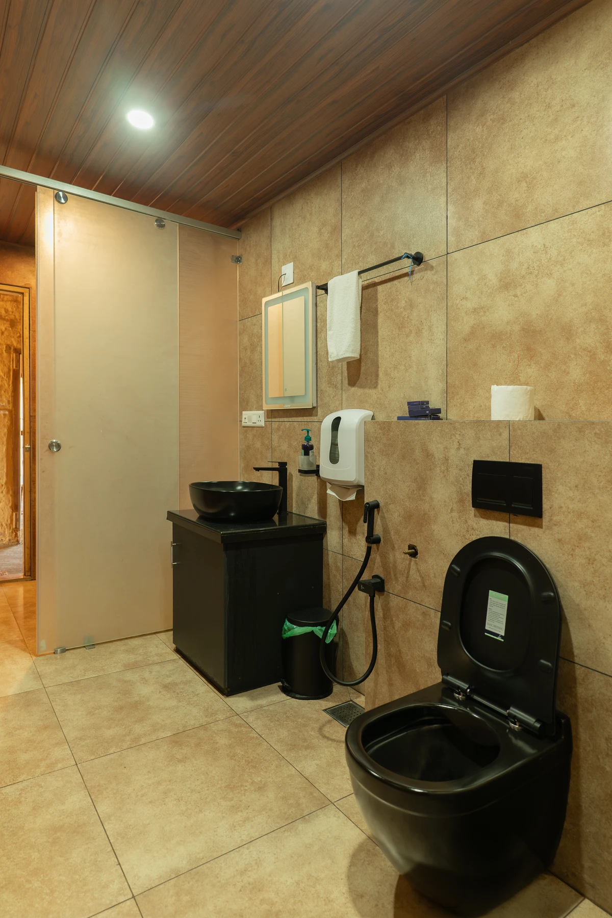 Sleek Shower Stall TModern shower area with a sleek black shower panel and textured tiles at boCHE 1000 Acre, one of the best resorts in Wayanad.