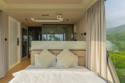 Luxury double bed with floor-to-ceiling plantation views inside xpod boche 1000 acre resort wayanad