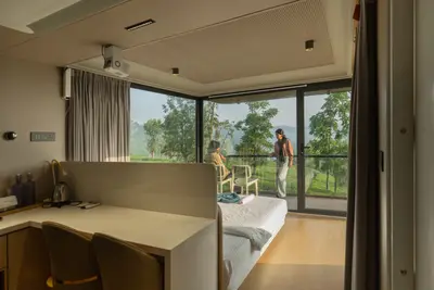 Luxury double bed with floor-to-ceiling plantation views inside xpod boche 1000 acre resort wayanad