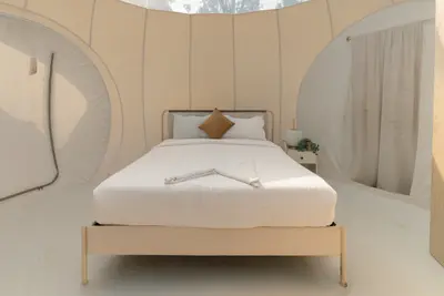 Cozy premium bed setup inside a scenic glamping bubble dome at boCHE 1000 Acre resort in Wayanad.