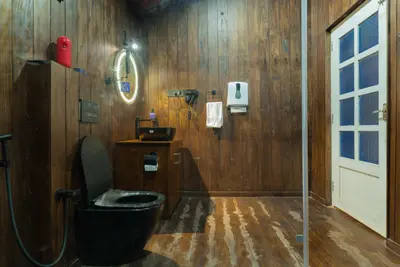 Modern wooden bathroom with a glass shower and LED mirror at boCHE 1000 Acre, one of the best resorts in Wayanad.