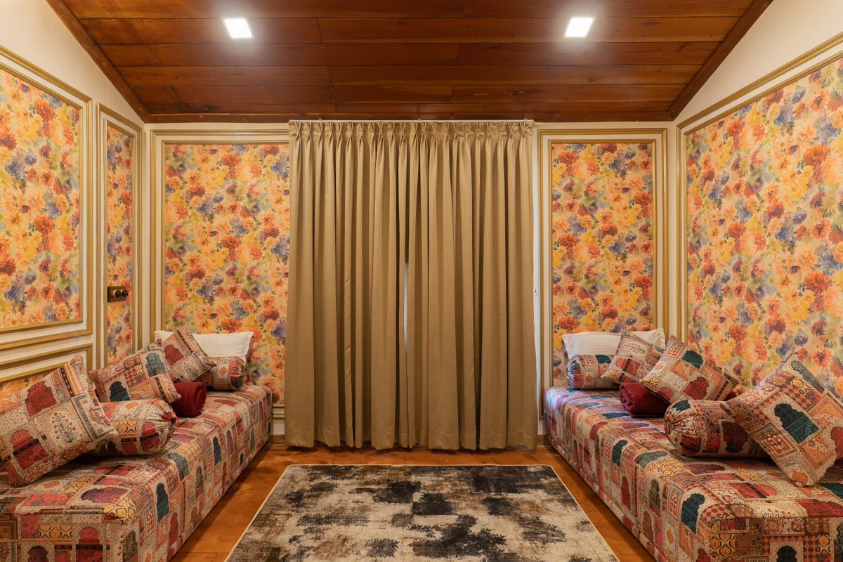 Cozy Lounge Room with Patterned Diwans Cozy lounge room with patterned diwans and floral wallpaper at boCHE 1000 Acre, one of the best resorts in Wayanad.
