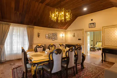 Elegant dining room with a luxury glass table and chandelier at boCHE 1000 Acre, one of the best resorts in Wayanad.