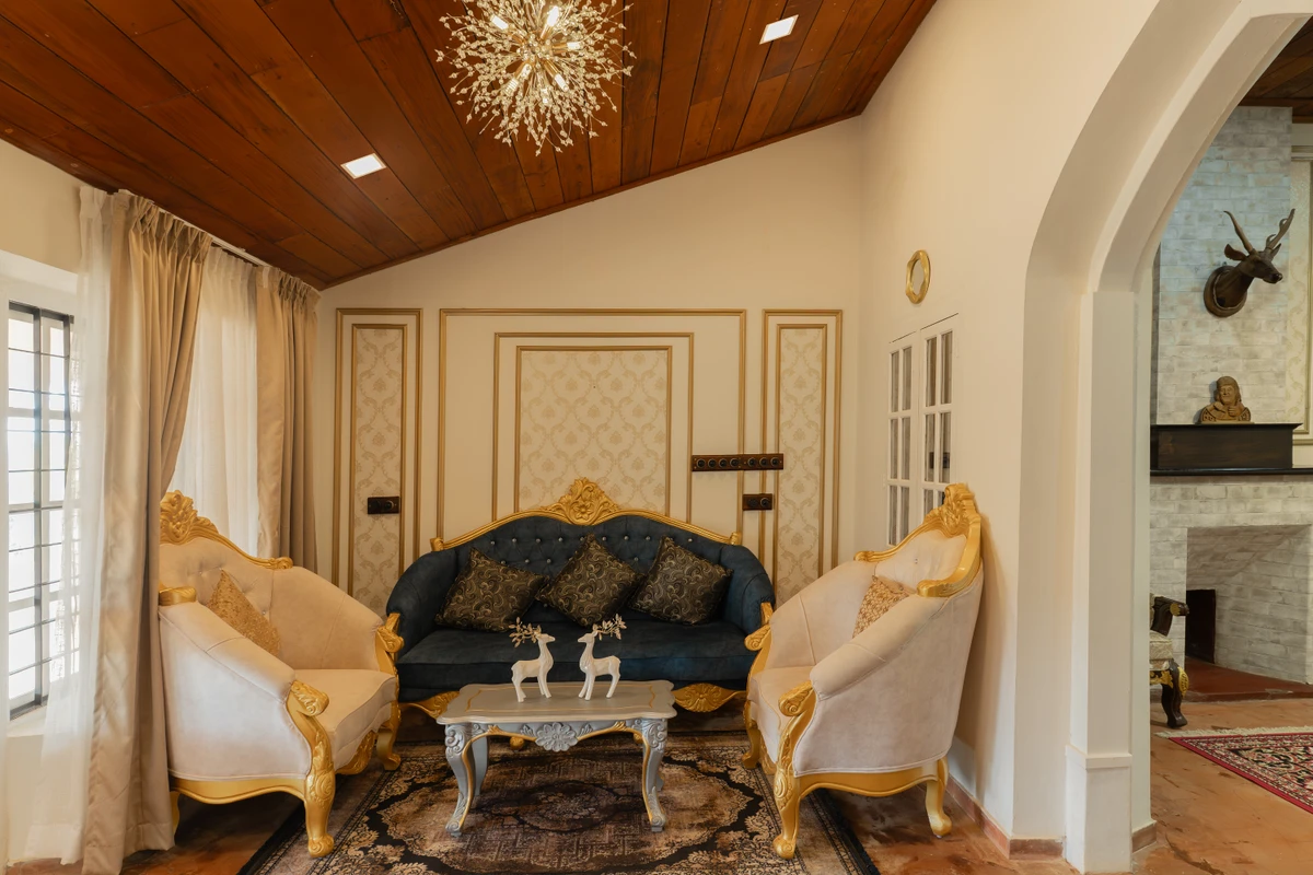 Gold-Trimmed Sofas in Royal Living Space Elegant living space with royal gold-trimmed sofas and a spiky chandelier at boCHE 1000 Acre, one of the best resorts in Wayanad.